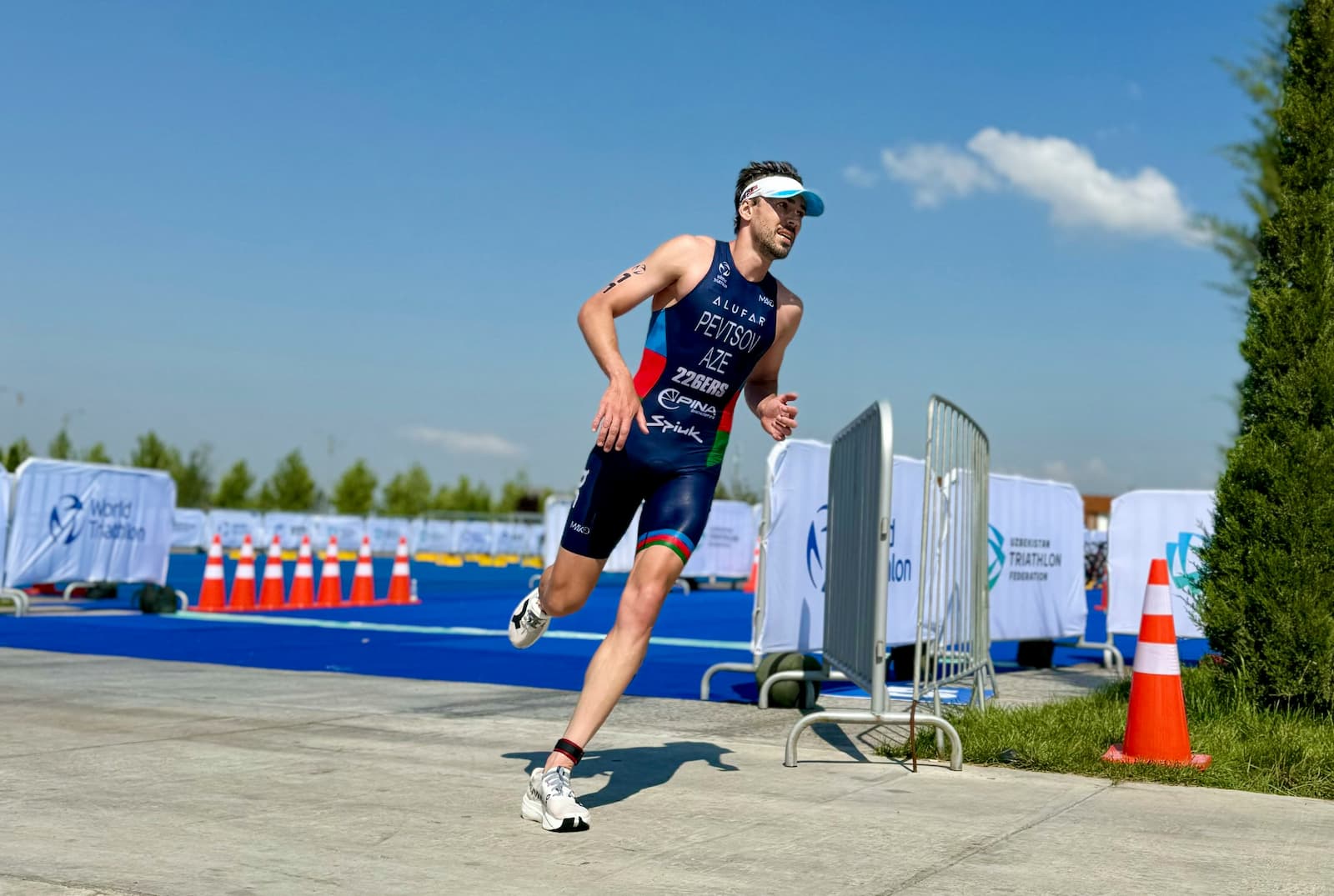 A triathlete running on a road during training, wearing performance gear and a watch, representing structured weekly triathlon planning and endurance preparation.