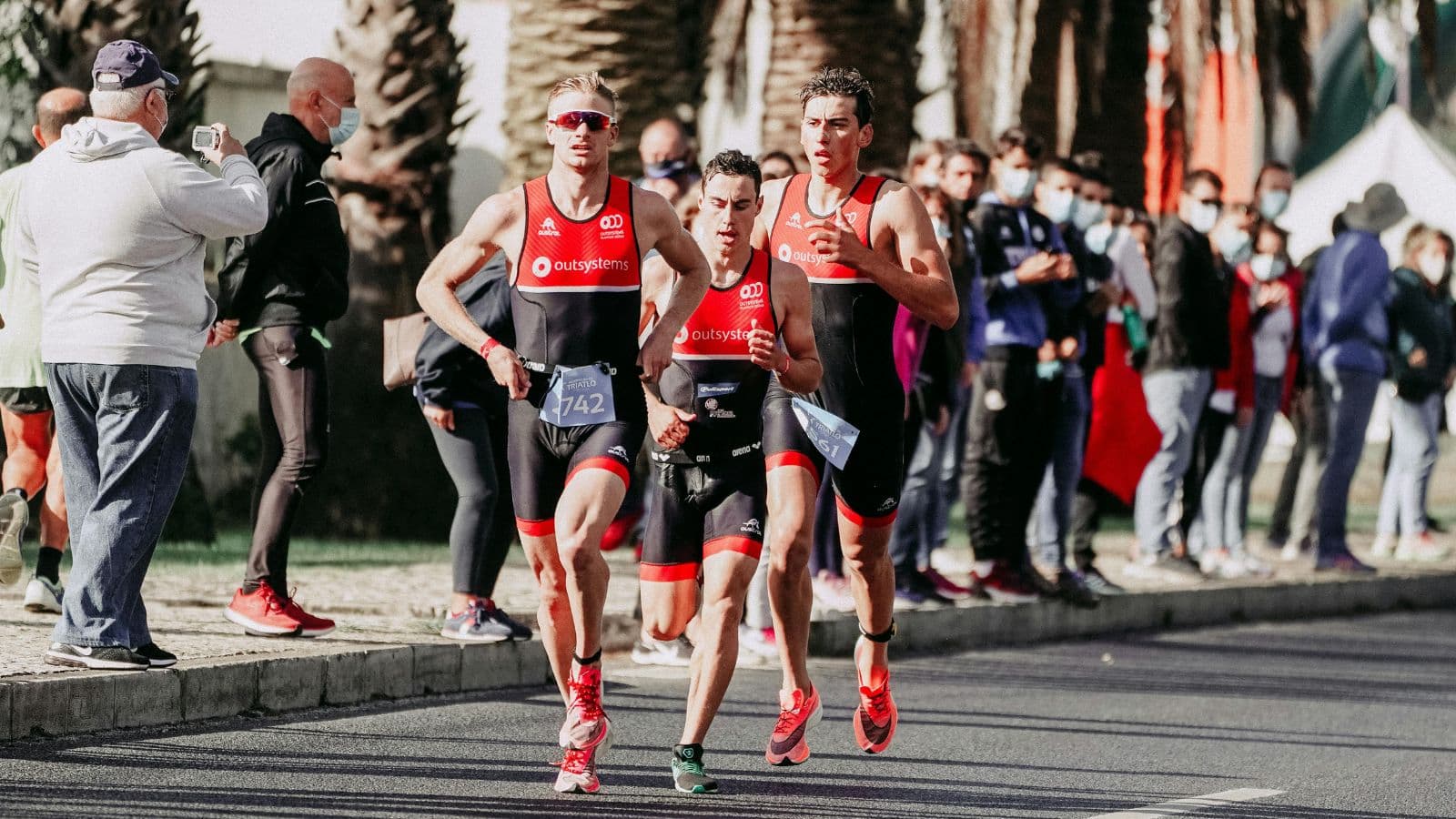 Triathletes running at high intensity during Olympic distance race, maintaining pace and efficient form