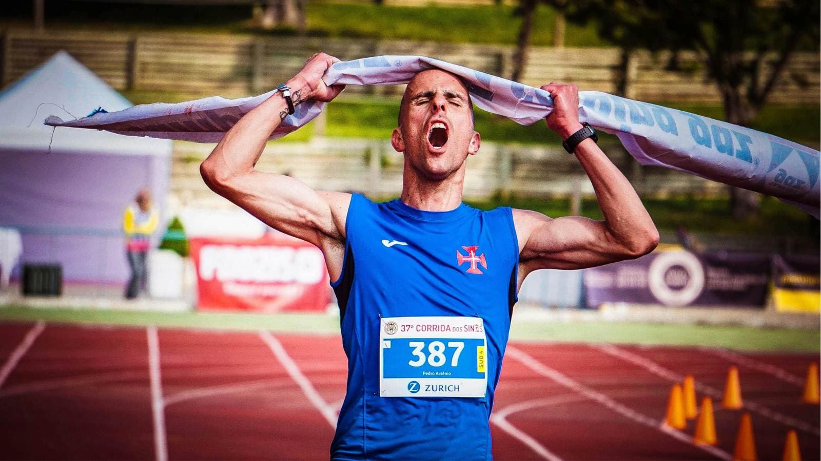 Triathlete crossing the finish line with arms raised, winning a race through strong pacing and endurance strategy
