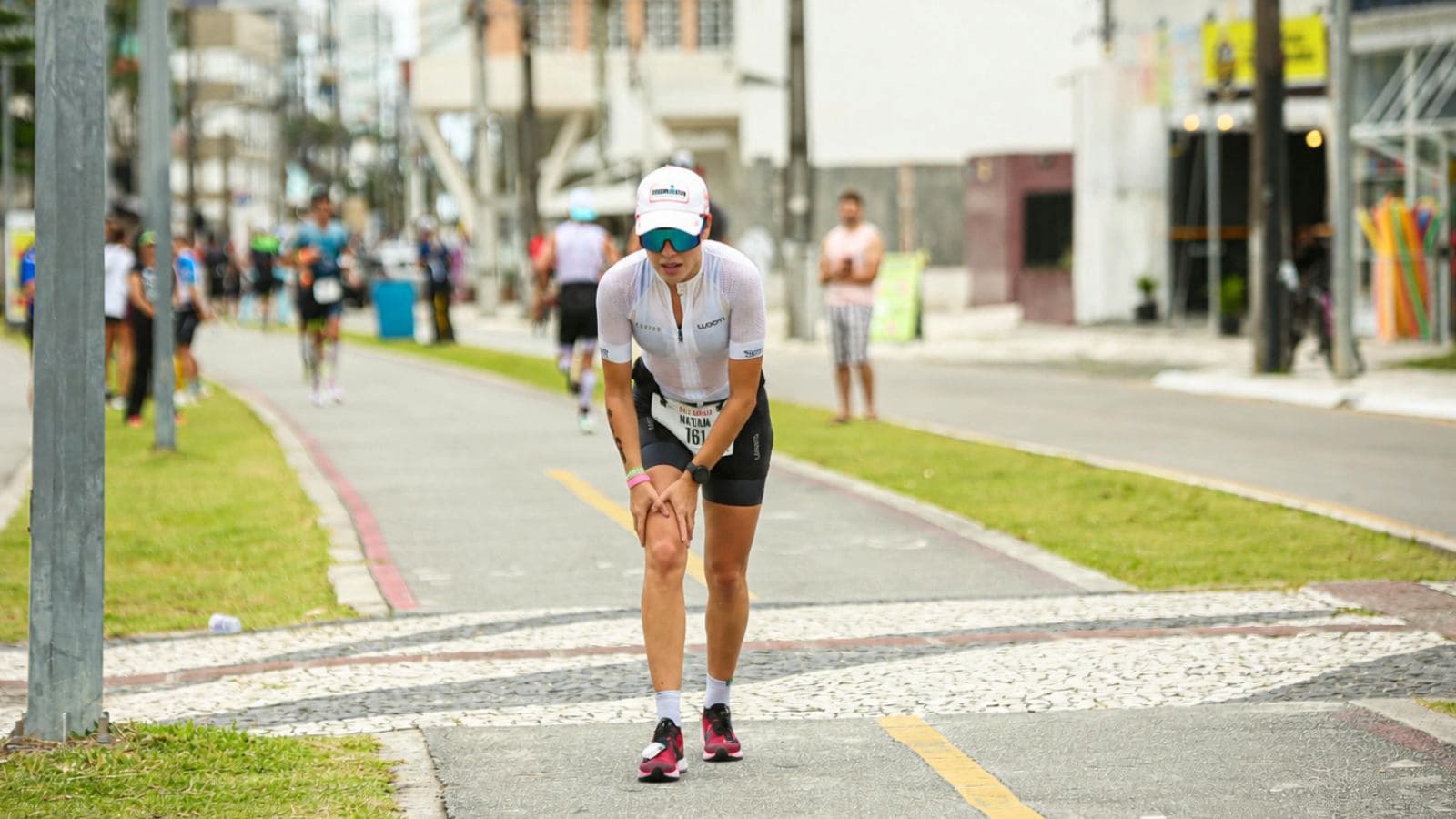 triathlete holding sore knee during race run after swim and bike segments